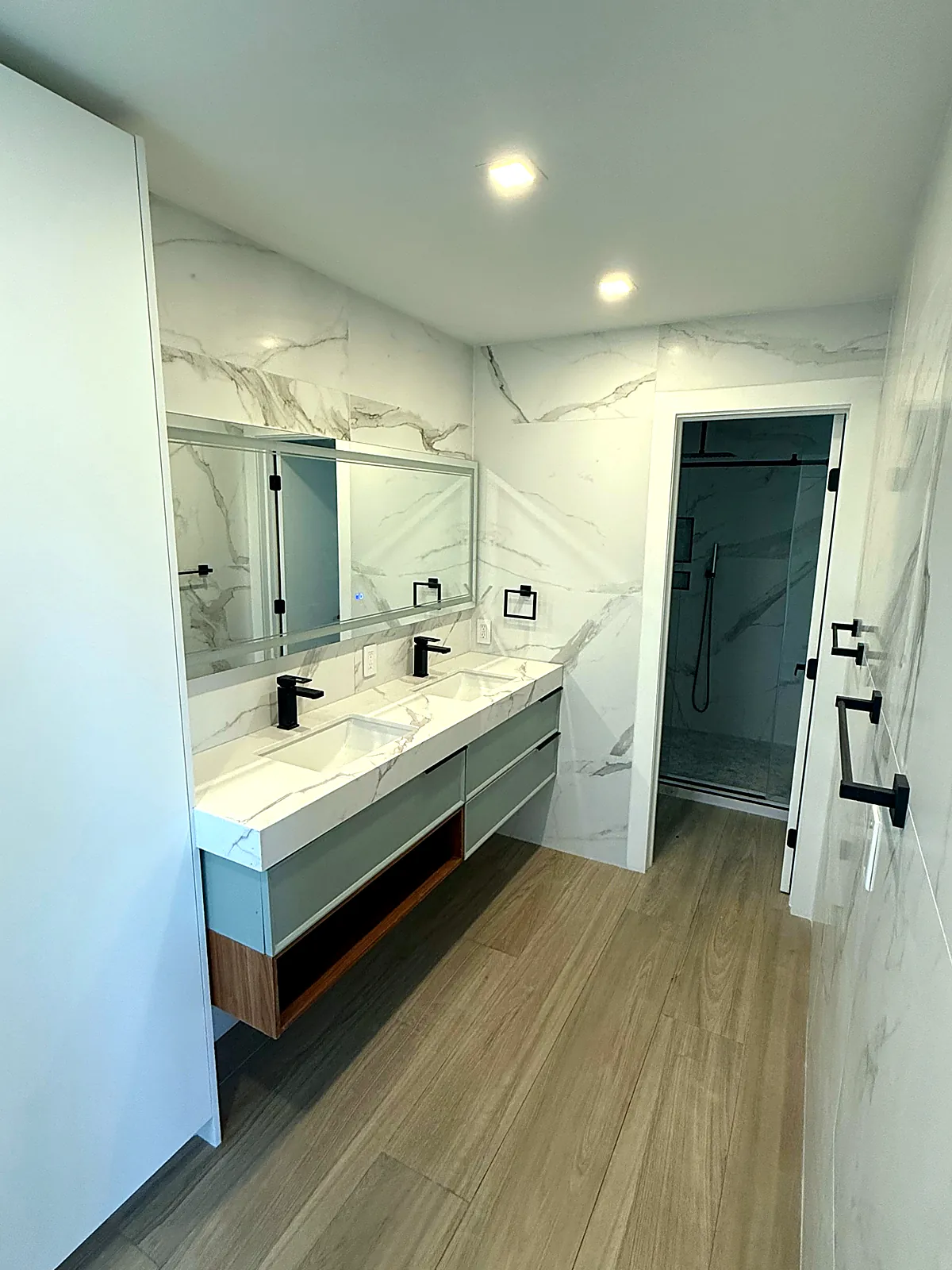 Bathroom with double floating vanity, large mirror, marble-look slab wall and fresh paint in Miami