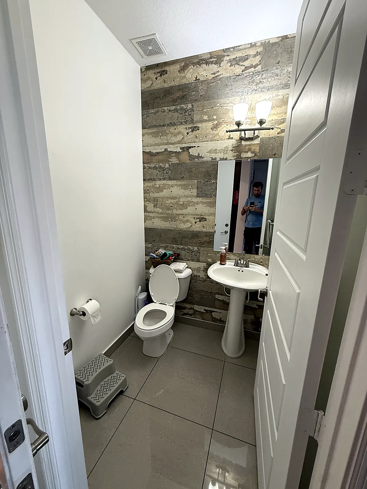 Medio baño antes de la renovación, con pared de madera reciclada y bacha de pie en Aventura