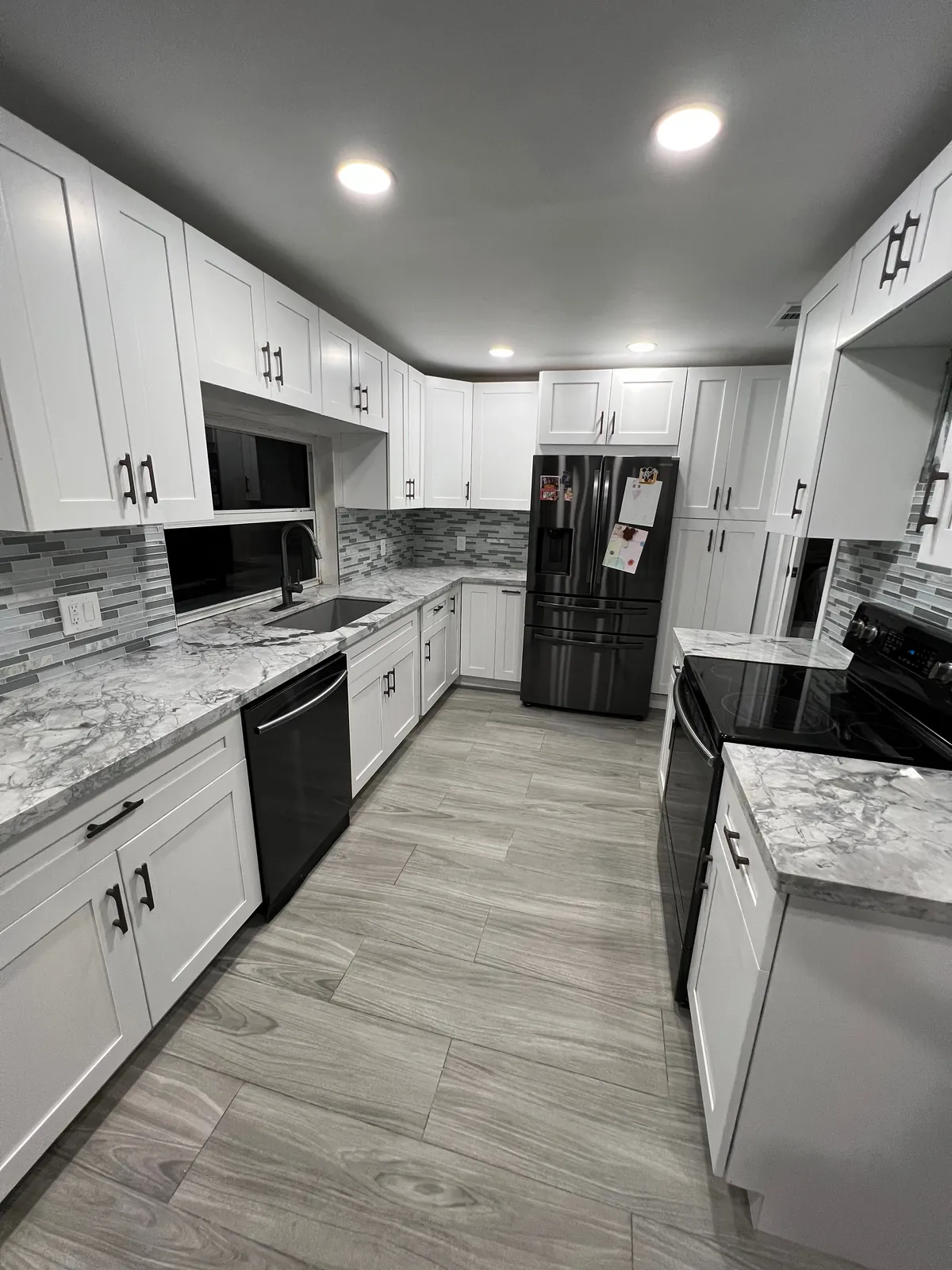 Finished white shaker kitchen with quartz counters, LED lighting, floor tile and mosaic backsplash in Miami